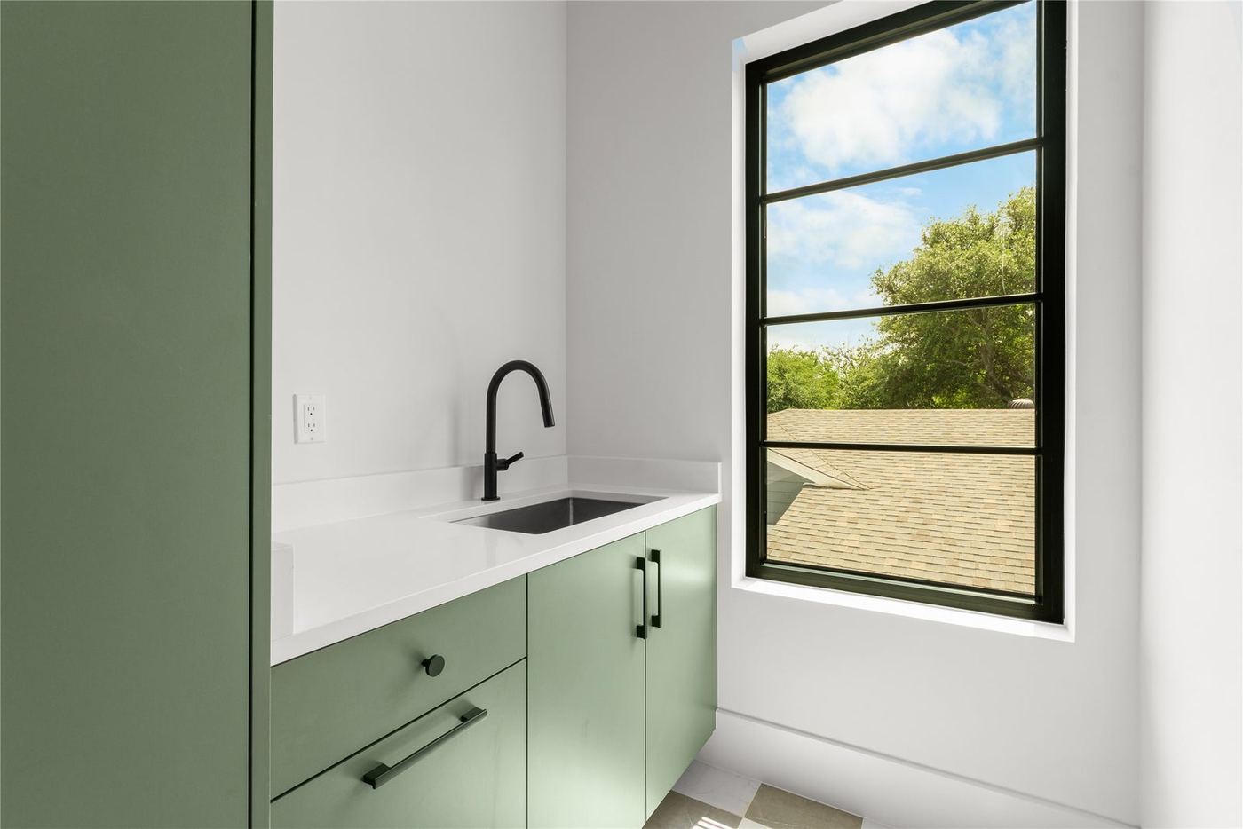 Large black-frame window over a green cabinet run